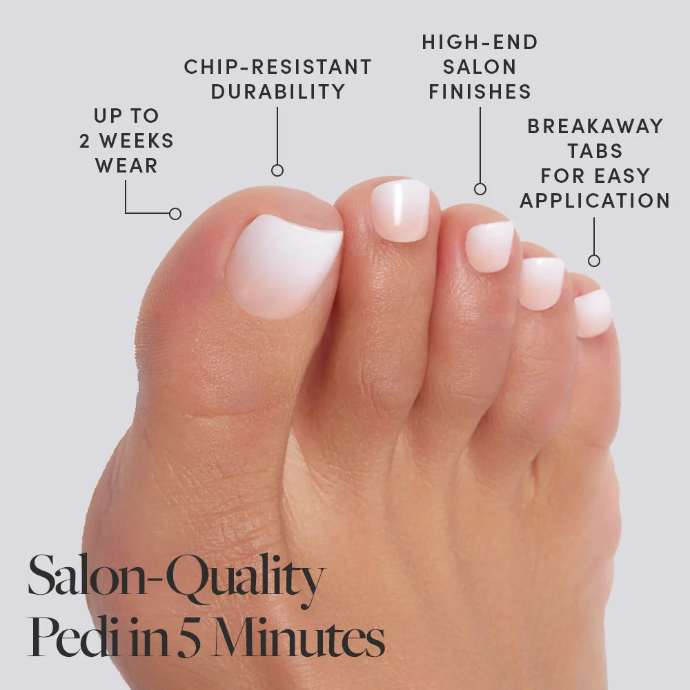 Close-up of white glossy Glamnetic press-on toenails, worn barefoot beside a pool in bright pink bow sandals and a gold toe ring.