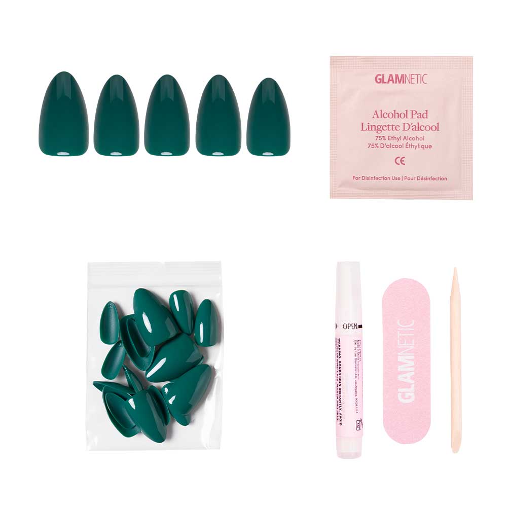The Emerald Green short almond press-on nails by glamnetic feature a glossy finish and come with extra nails, nail glue tube, alcohol pad, pink file, and a wooden cuticle stick, all displayed on a white background.