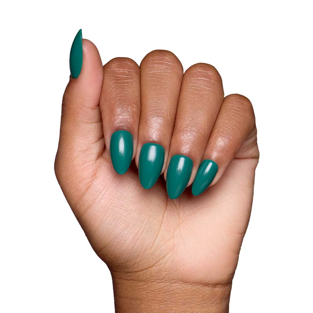A medium skin tone hand forms a fist, showcasing glamnetics Emerald Green short almond nails with a glossy finish against a white background.