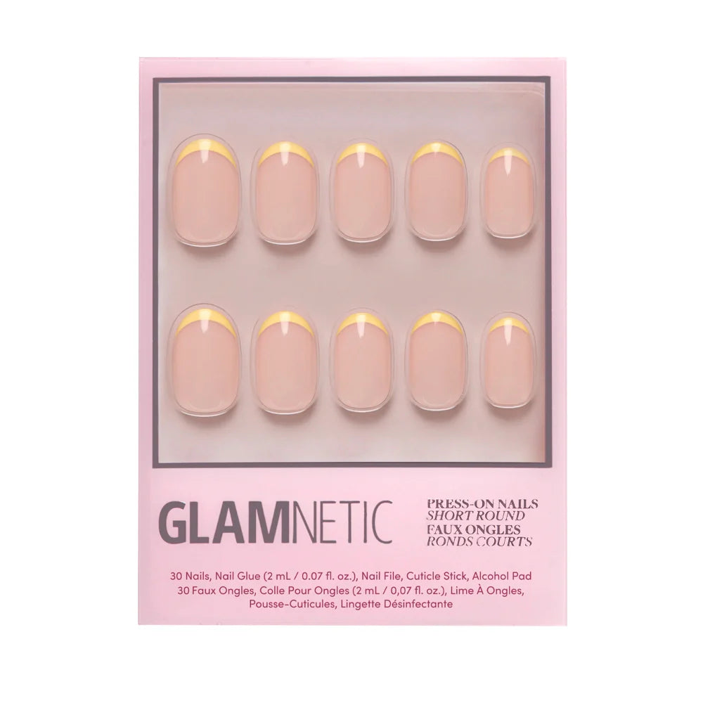 A pink glamnetic box displays the French Butter Press-On Nail Set: 10 short, round nails with a nude base and pastel yellow French tips. Includes nail glue, file, cuticle stick, and alcohol pad for salon-quality durability.