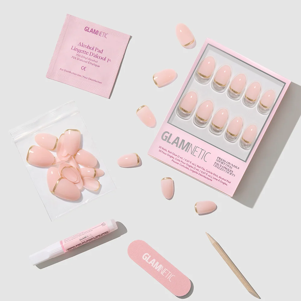 The Glam Goals set by glamnetic features pink short oval press-on nails with gold foil French tips, a pink nail file, glue, alcohol pad, and extra nails, all arranged neatly on a white surface with glamnetic branding.