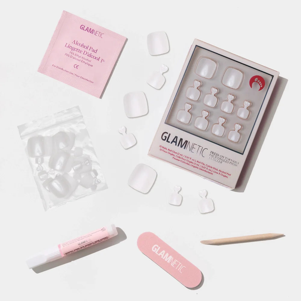 A flat-lay of the Glamnetic clean white press-on toenail kit with a glossy finish and included tools for application.