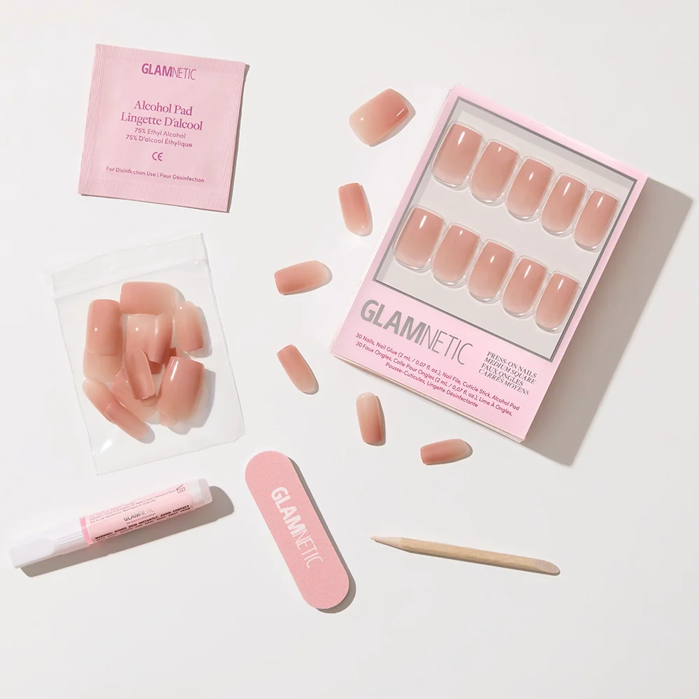 The glamnetic In The Nude set includes nude-pink ombré press-on nails in a pink case, plus a nail file, cuticle stick, glue, alcohol pad, and extra nails—everything needed for an easy minimalist manicure.