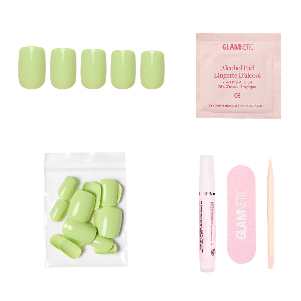 The glamnetic Light Sage Nail Set includes glossy short squoval nails, an alcohol pad, extra green nails in a clear pouch, nail glue, a pink nail file, and a wooden cuticle stick—displayed on a white background.