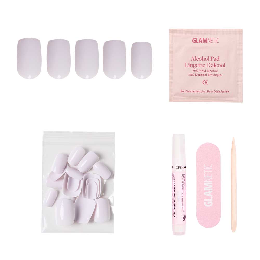 The Lilac Gray nail kit by glamnetic includes pale pink squoval nails with a glossy finish, an alcohol pad, nail file, cuticle stick, glue, and extra nails in a clear bag—neatly arranged on a white background.
