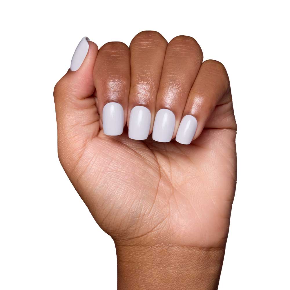 A medium brown-skinned hand forms a fist, showing squoval nails painted with glamnetic’s Lilac Gray polish in a glossy finish against a white background.