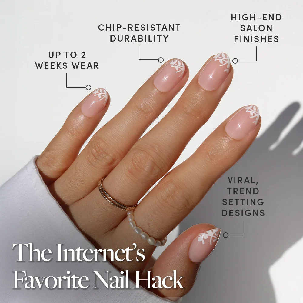 A hand with manicured nails wears glamnetic’s Love Preserved: nude polish with a delicate white leaf design. Enjoy up to 2 weeks wear, chip-resistant durability, salon-quality finish, and viral botanical nail art.