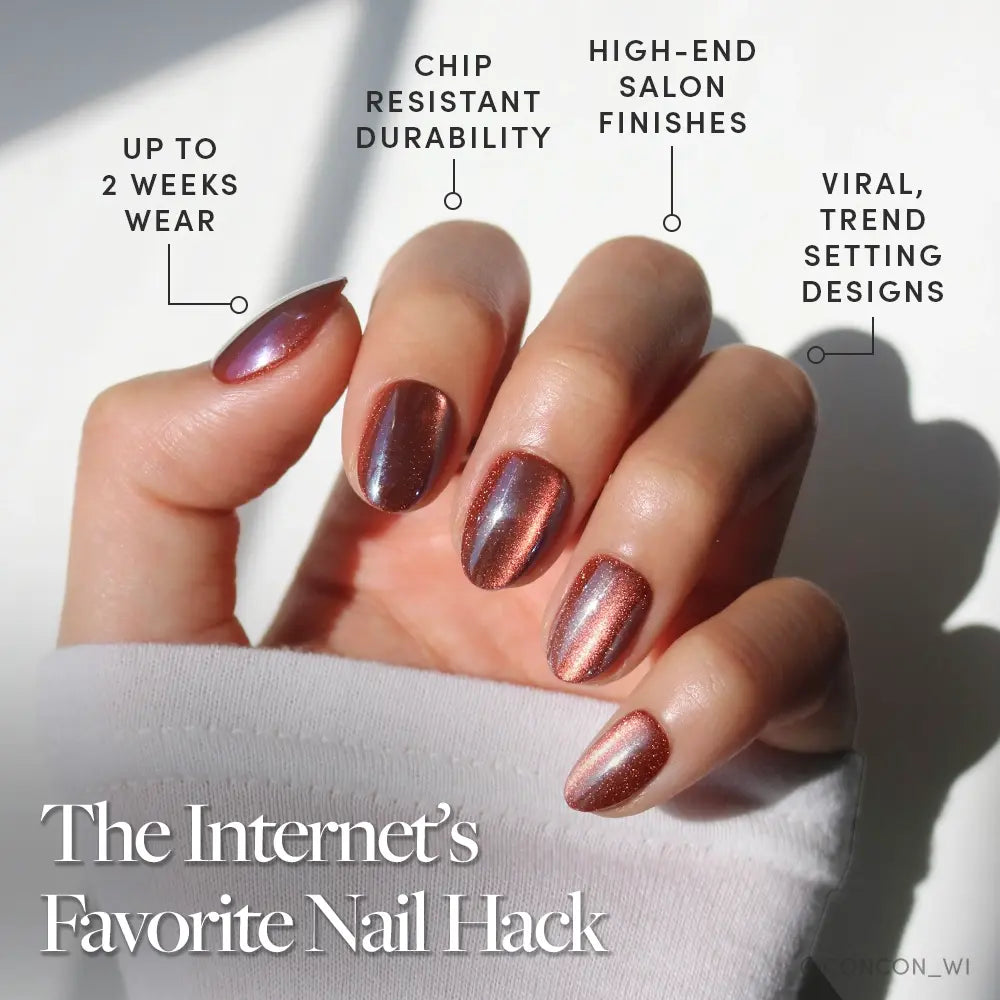 A hand with shiny, metallic rose gold Magnetic Moscow cat-eye nails by glamnetic rests on a white sleeve. Enjoy up to 2 weeks wear, chip-resistant durability, high-end salon finishes, and viral, trend-setting designs.