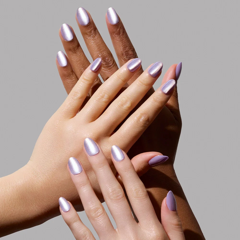 Three hands with varied skin tones display manicured nails painted in glamnetic’s Mermaids Tail, an iridescent purple polish, against a plain gray background. Their elegant overlap perfectly showcases the dazzling nail color.