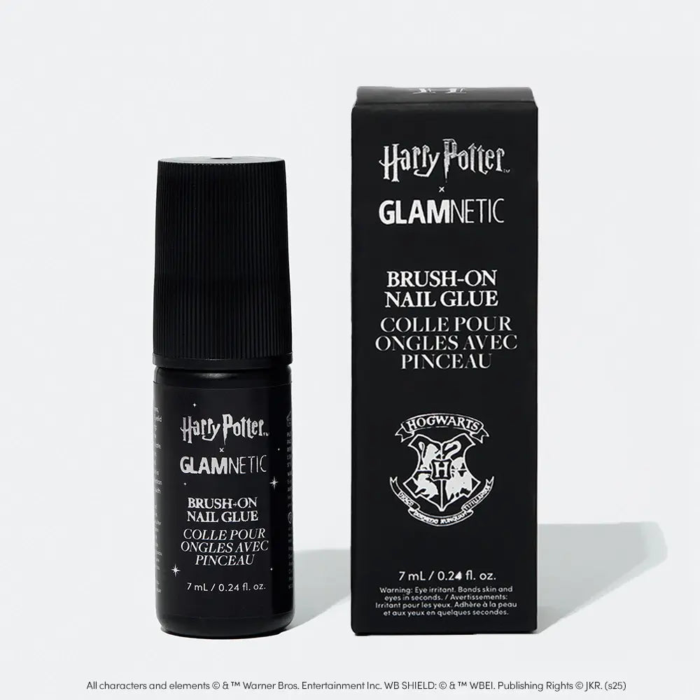 A bottle and box of glamnetic’s Harry Potter™ x Glamnetic Brush-On Nail Glue, both in black with white text and a Hogwarts crest, are shown on a light gray background—ideal for easy press-on nail application.