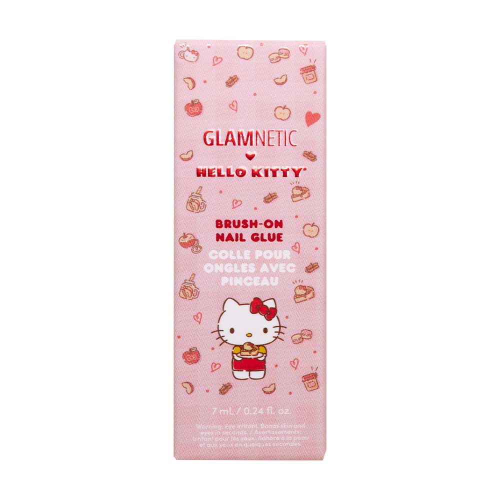 A pink box of glamnetic Hello Kitty™ Brush-On Nail Glue, 7 mL (0.24 fl. oz.), features apple, bow, and heart designs plus English and French text—perfect for at-home manicures.