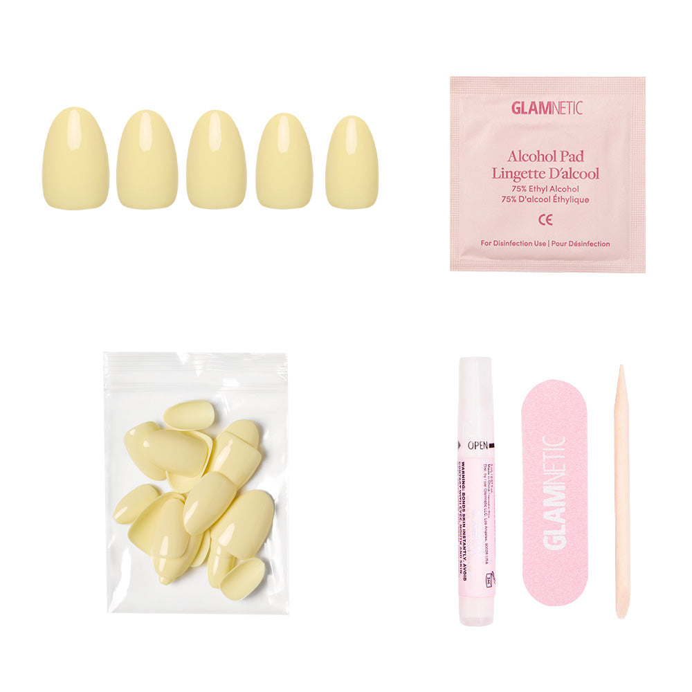 The glamnetic Pastel Yellow Nail Set includes short oval nails with a salon-quality sheen, an alcohol pad, extra nails in a small bag, nail glue, a pink file, and a wooden cuticle stick—all displayed on a white background.