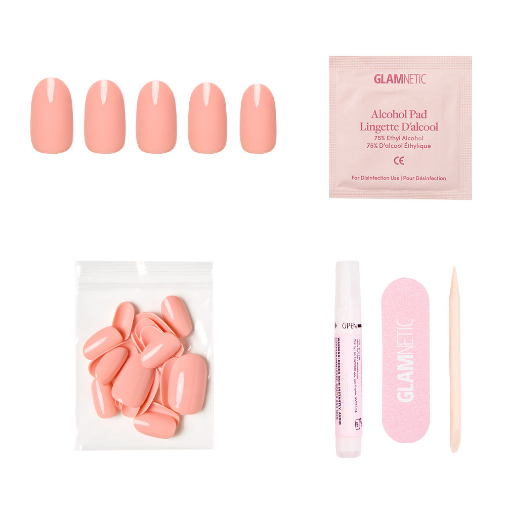 The Peach Coral Nail Set by glamnetic features reusable pastel peach nails, extra nails, nail glue, an alcohol pad, a pink file, and a wooden cuticle stick—all arranged on a white background.