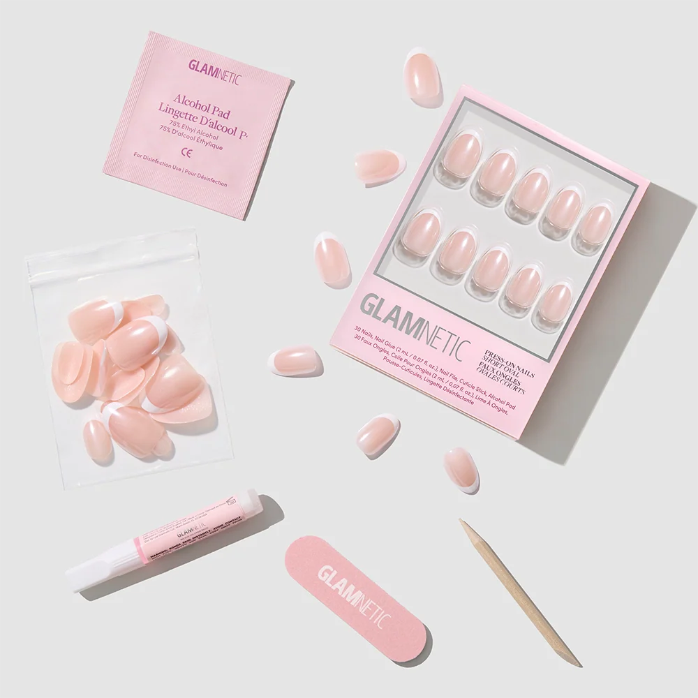 The glamnetic Pearlfect set features pink pearlescent press-on nails, a nail file, cuticle stick, glue, alcohol pad, and extra nails—all arranged neatly on a light gray background.