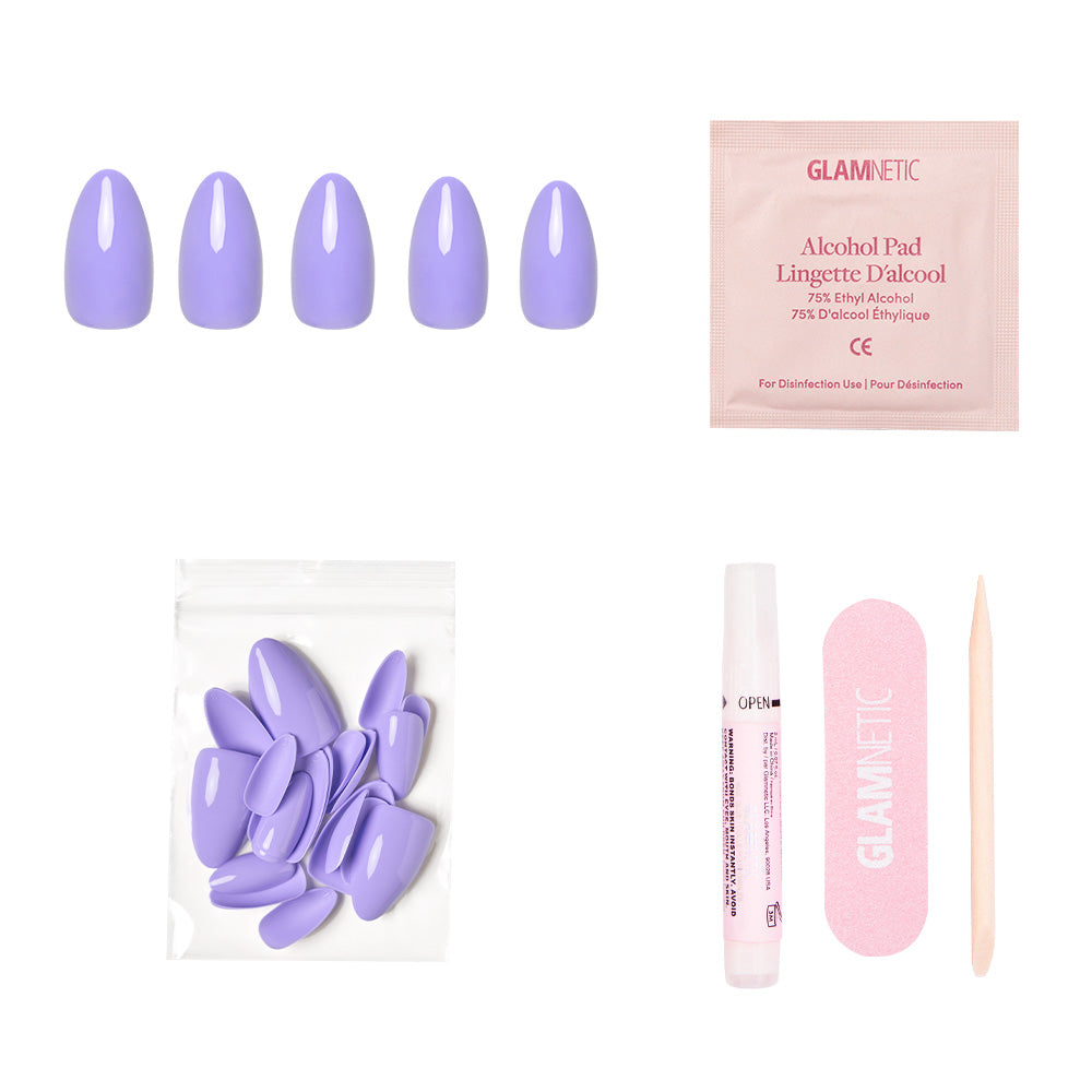 The Periwinkle press-on nails set by glamnetic includes glossy nails, an alcohol pad, extra nails, a nail glue tube, a pink file, and a wooden cuticle stick neatly arranged on a white background.
