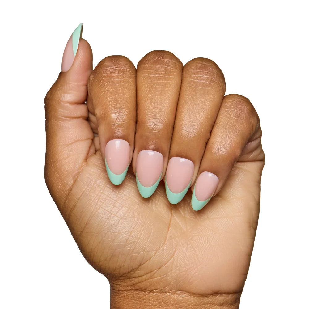 A hand with medium brown skin showcases salon-quality nails created with glamnetics Pistachio Crème, a chic nude base paired with light green French tips, set against a white background.