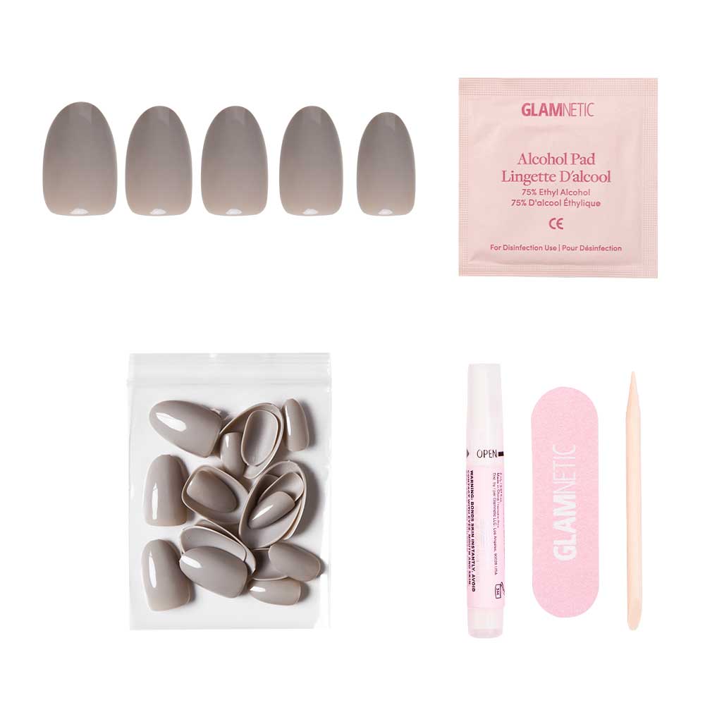The glamnetic Pure Gray Nail Set includes taupe and gray glossy nails, an alcohol pad, extra nails in a resealable bag, nail glue, a pink file, and a wooden cuticle stick—all arranged on a white background.