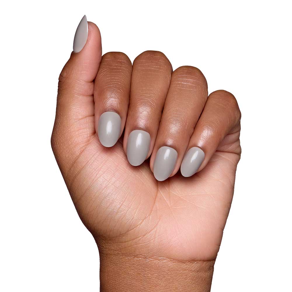A hand with medium brown skin displays neatly manicured gray nails in a glossy finish from glamnetic’s Pure Gray set, shown against a white background.