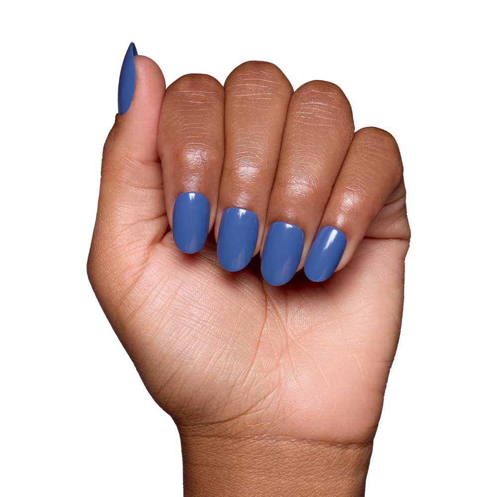 A hand with medium brown skin and neatly manicured nails painted in Regal Blue—a vegan, cruelty-free polish—shows off the glossy blue shade against a plain white background.