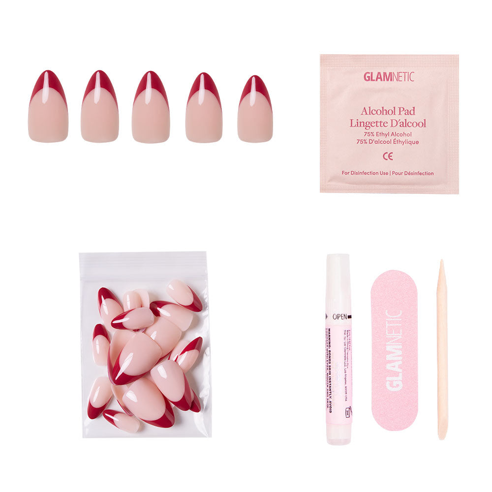 The Rose Garden by glamnetic includes short almond nails with deep red tips, extra nails, an alcohol pad, cuticle stick, nail file, and adhesive—everything arranged on a white background.