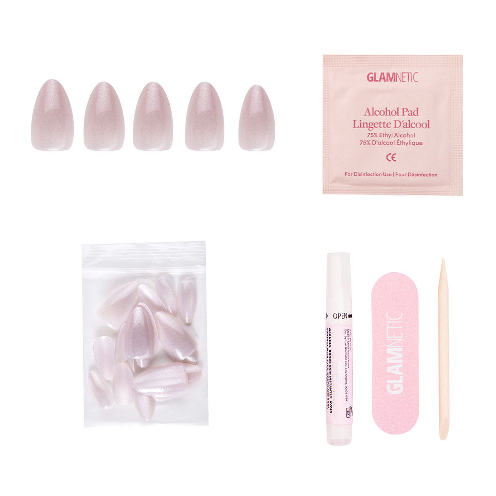 The glamnetic Selenite Nail Set includes five short almond-shaped pink nails, extra nails, an alcohol pad, glue tube, pink nail file, and wooden cuticle stick—all arranged on a white background.