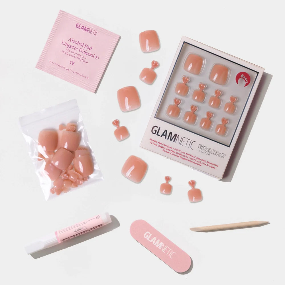 A flat-lay of the Glamnetic peach press-on toenail kit, including nails, glue, nail file, cuticle stick, and alcohol pad.