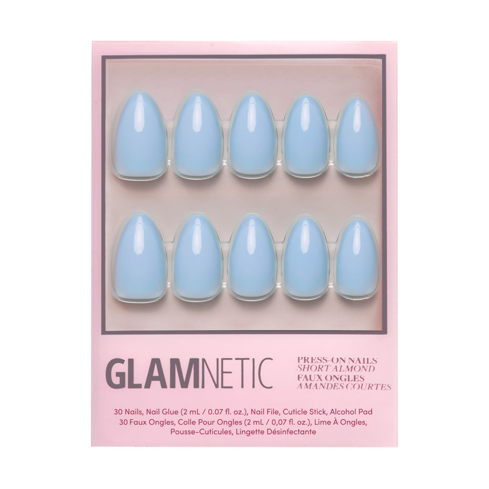 The Soft Blue Nail Set by glamnetic showcases ten short almond-shaped, glossy press-on nails in pink glamnetic packaging. Accessories and instructions are listed at the bottom of the box.