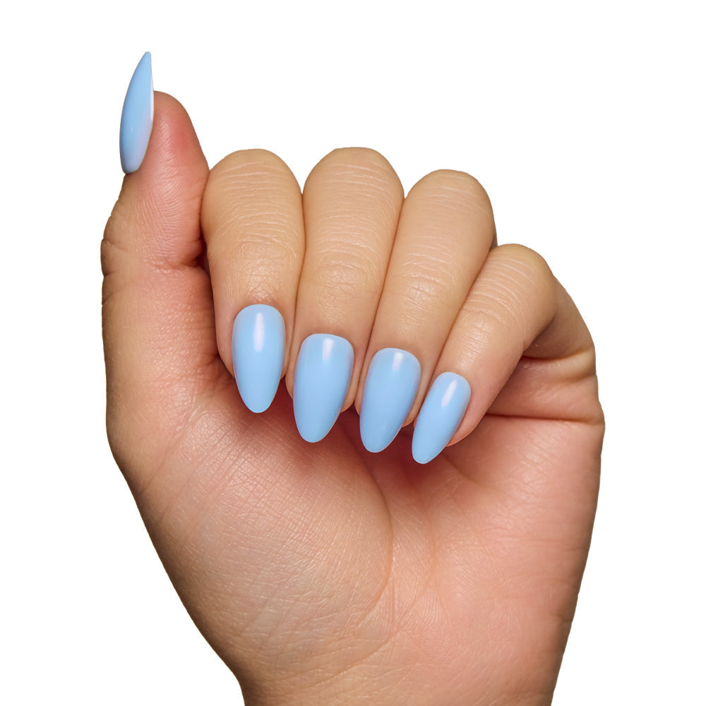 A hand displays the glamnetic Soft Blue short almond nails with a glossy finish against a white background.