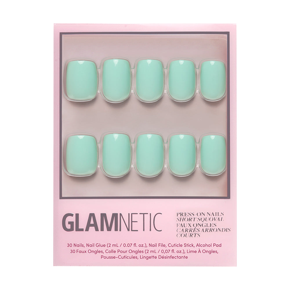 A set of Soft Teal short squoval press-on nails by glamnetic, arranged in two rows inside pink packaging with manicure tools and accessories listed at the bottom.