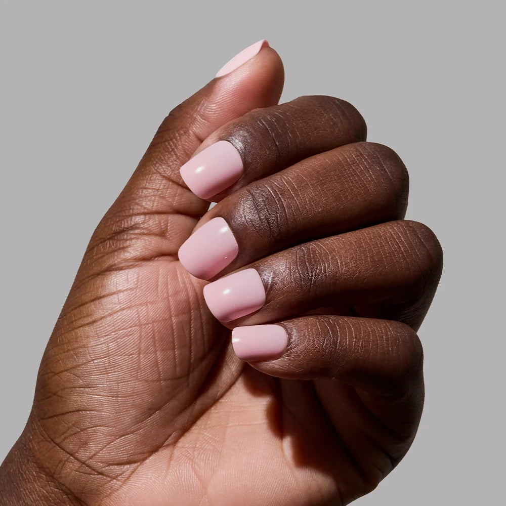 A hand with super short nails shows off a classic pink mani using glamnetic’s Sugar BB.