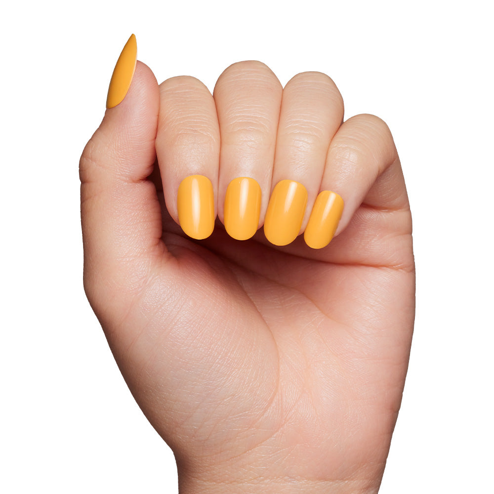 A hand with neatly manicured nails painted in glamnetic’s Sunset Orange pops against a white background—ideal for making a bold, citrus-inspired statement.