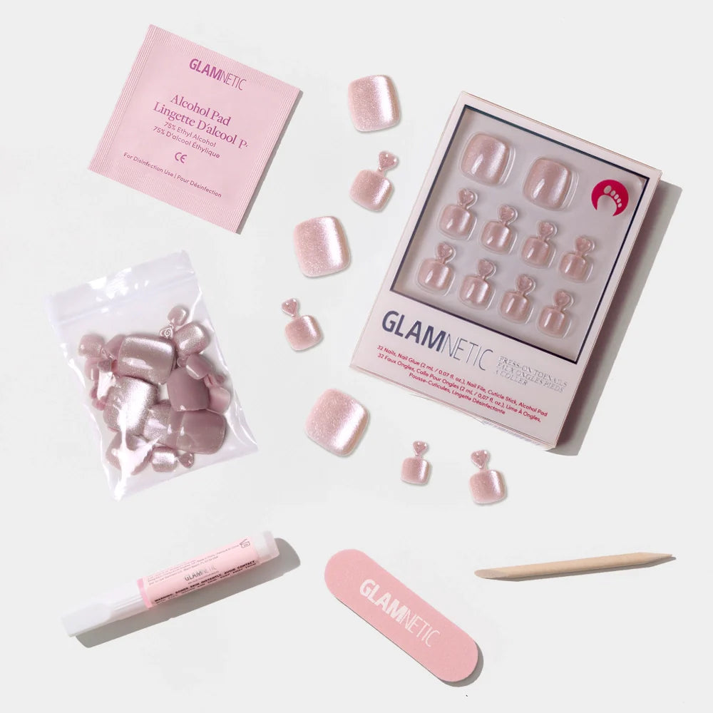 A flat-lay of the Glamnetic shimmery nude pink press-on toenail kit with nail prep tools and extra nails.