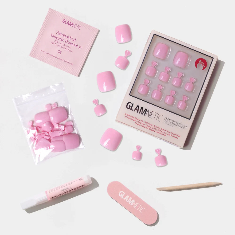 A flat-lay of the Glamnetic pastel pink press-on toenail kit, featuring nails, glue, file, stick, and alcohol pad.