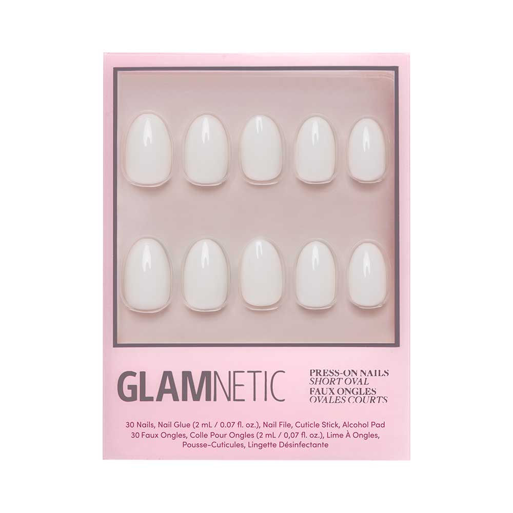 A pink box labeled “glamnetic” holds the White Swan Nail Set—ten short, oval, light pink glossy press-on nails in two rows. English and French text on the box describes the product and its contents.