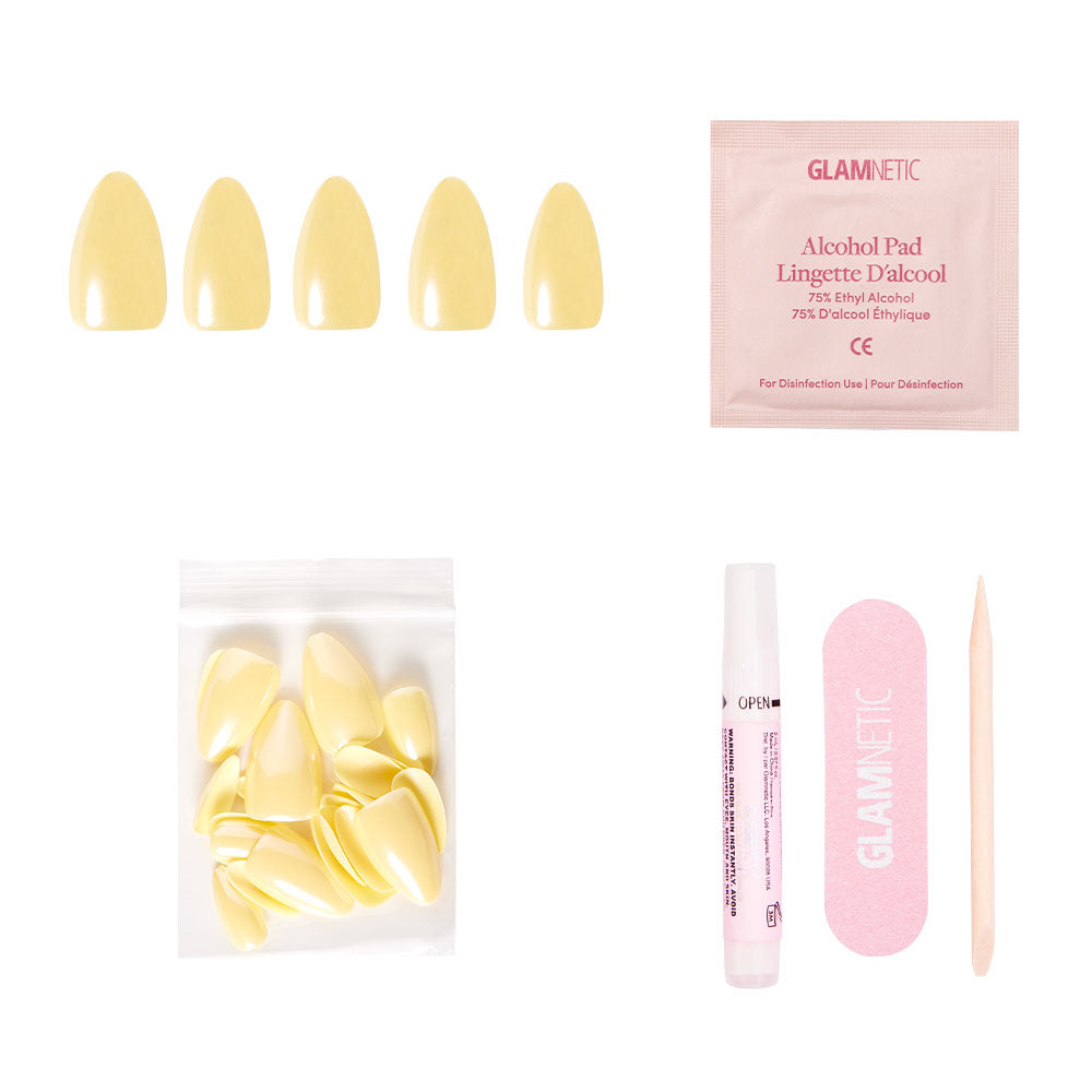 The glamnetic Yellow Pop nail set includes pastel yellow press-ons, an alcohol pad, extra nails, nail glue, a pink file, and a wooden cuticle stick, all displayed on a white background.