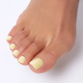 UGC A close-up of a foot showcasing Glamnetic press-on toenails in a creamy pastel yellow shade with a glossy finish for a soft, sunny look.